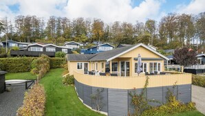 Une maison jaune avec un patio couvert et une cour clôturée.