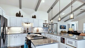 Une cuisine spacieuse avec des meubles blancs, un grand îlot central et une cuisinière moderne.