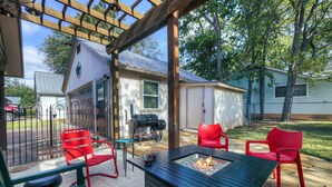 Une terrasse avec un foyer, des chaises rouges et une structure en forme de pergola.
