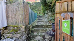 Un escalier étroit en pierre mène à une porte en bois sur laquelle est apposée une plaque portant l’inscription « Casa Botty ».