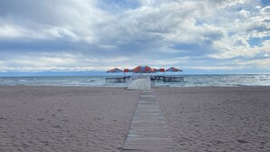 A beach with a wooden walkway leading to a series of overwater bungalows. - Baytur Resort & Spa (Cholpon-Ata)