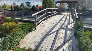 A wooden deck with a gazebo, stone walls, and a small building in the background. - Baytur Resort & Spa (Cholpon-Ata)
