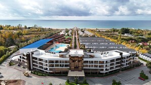 A modern hotel with a central courtyard, multiple buildings, and a view of the sea. - Baytur Resort & Spa (Cholpon-Ata)