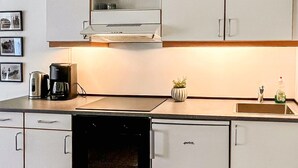 A modern kitchen with a dishwasher, a coffee maker, a sink, and a cabinet with a label. - Lovely apartment in Nexø with WiFi (Nexø)