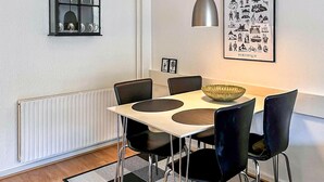 A dining area with a table, chairs, a bowl, a pendant light, a window with glassware, and a framed picture on the wall. - Lovely apartment in Nexø with WiFi (Nexø)