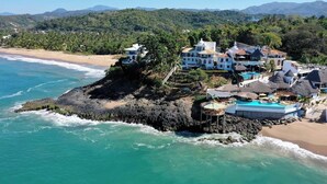 Una propiedad costera con una isla rocosa, una piscina y una playa.