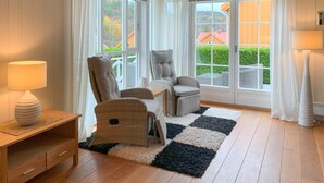 A cozy room with a large window, a chair, a small table, and a rug.