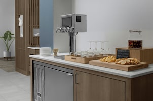 A kitchenette with a coffee machine, wine glasses, and a chalkboard menu listing food items.