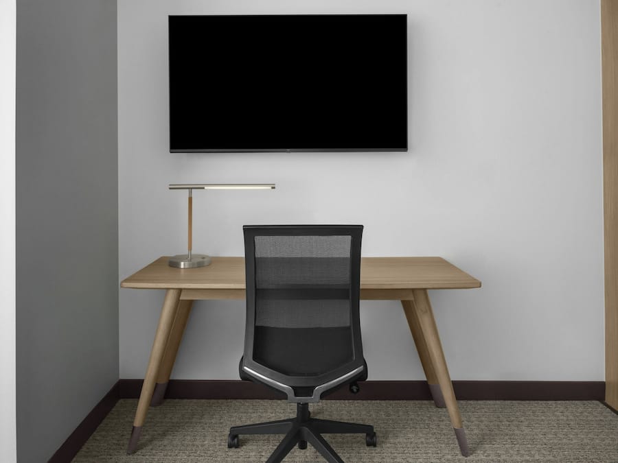 A workspace with a desk, chair, and a mounted television.