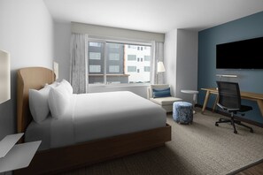 A hotel room with a large bed, a desk, a chair, a TV, and a window with a view of buildings. - Element by Marriott North Austin Tech Ridge (Austin)