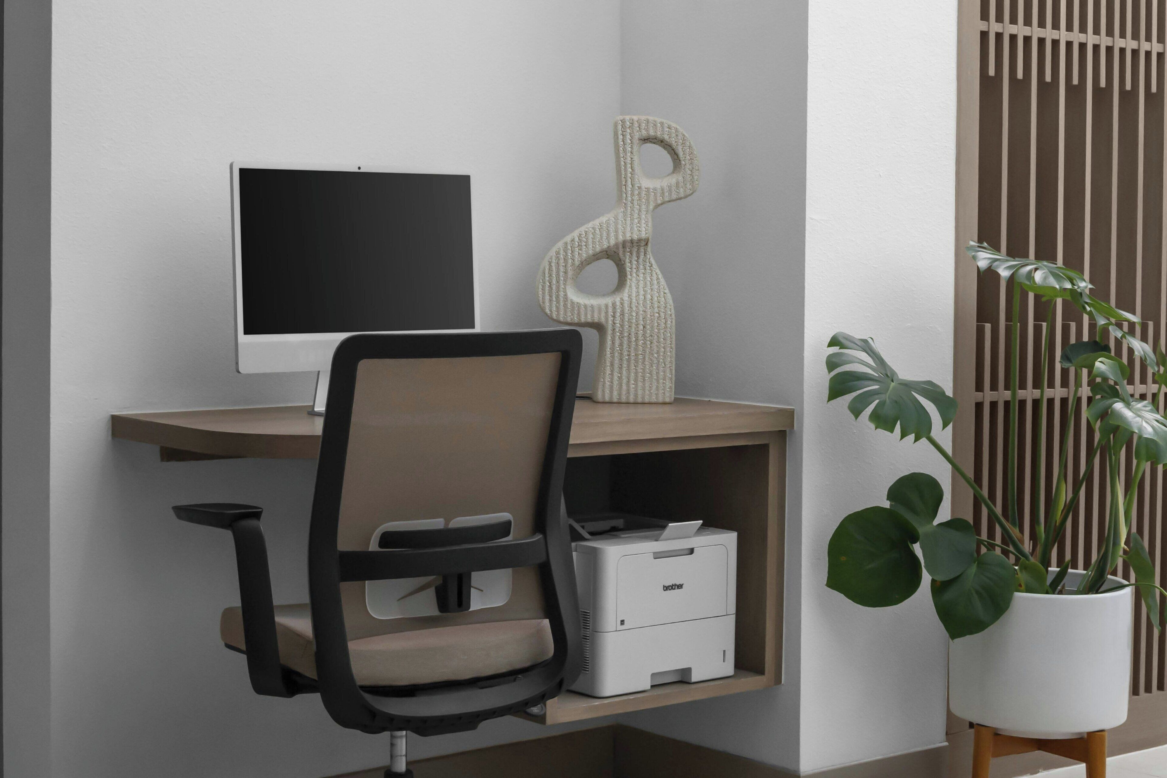 Un espacio de trabajo con un monitor de computadora, una impresora y una silla.