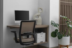 A workspace with a computer monitor, a printer, and a chair.