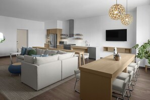 A modern kitchen with a dining area, a sofa set, and a TV mounted on the wall. - Element by Marriott North Austin Tech Ridge (Austin)
