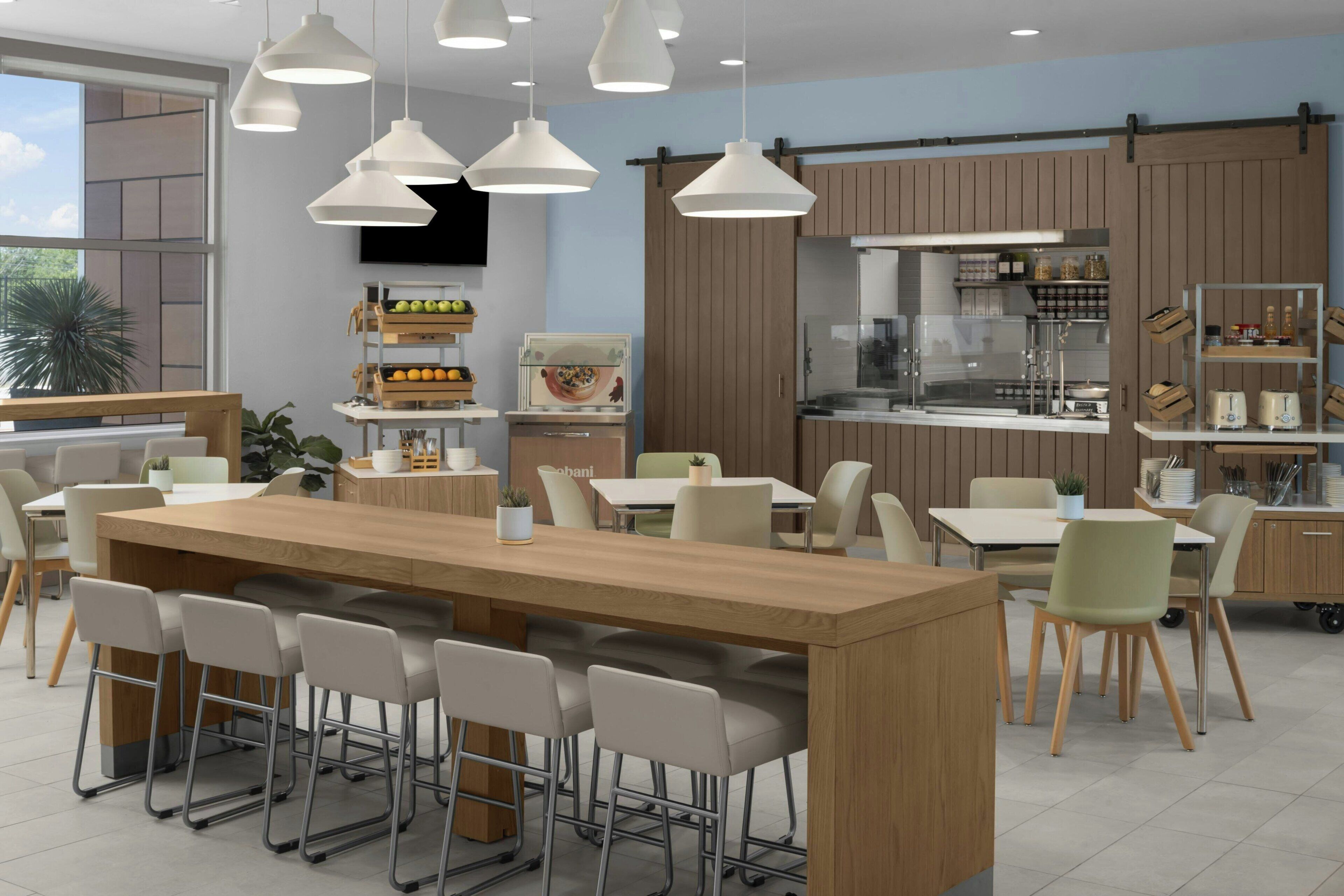 A modern kitchen with wooden cabinets, a central island with bar stools, and pendant lighting.