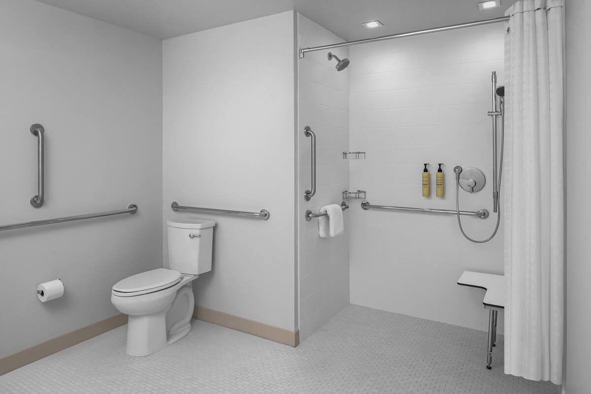 A bathroom with a toilet, shower, and grab bars.