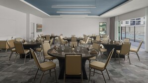 Ein Konferenzraum mit einem großen runden Tisch, mehreren Stühlen und modernen Leuchten.
