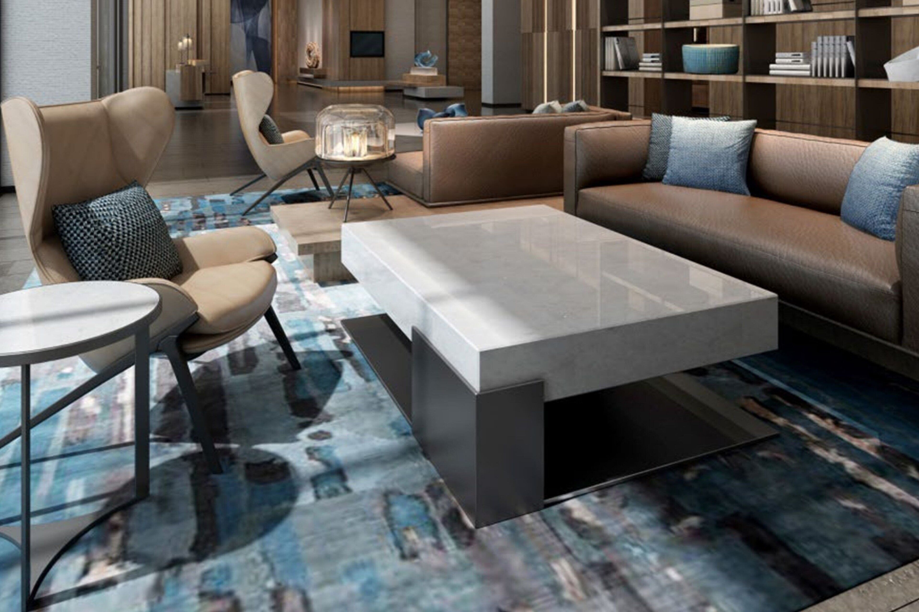 Een moderne woonkamer met een bank, fauteuils, een salontafel en een boekenkast.