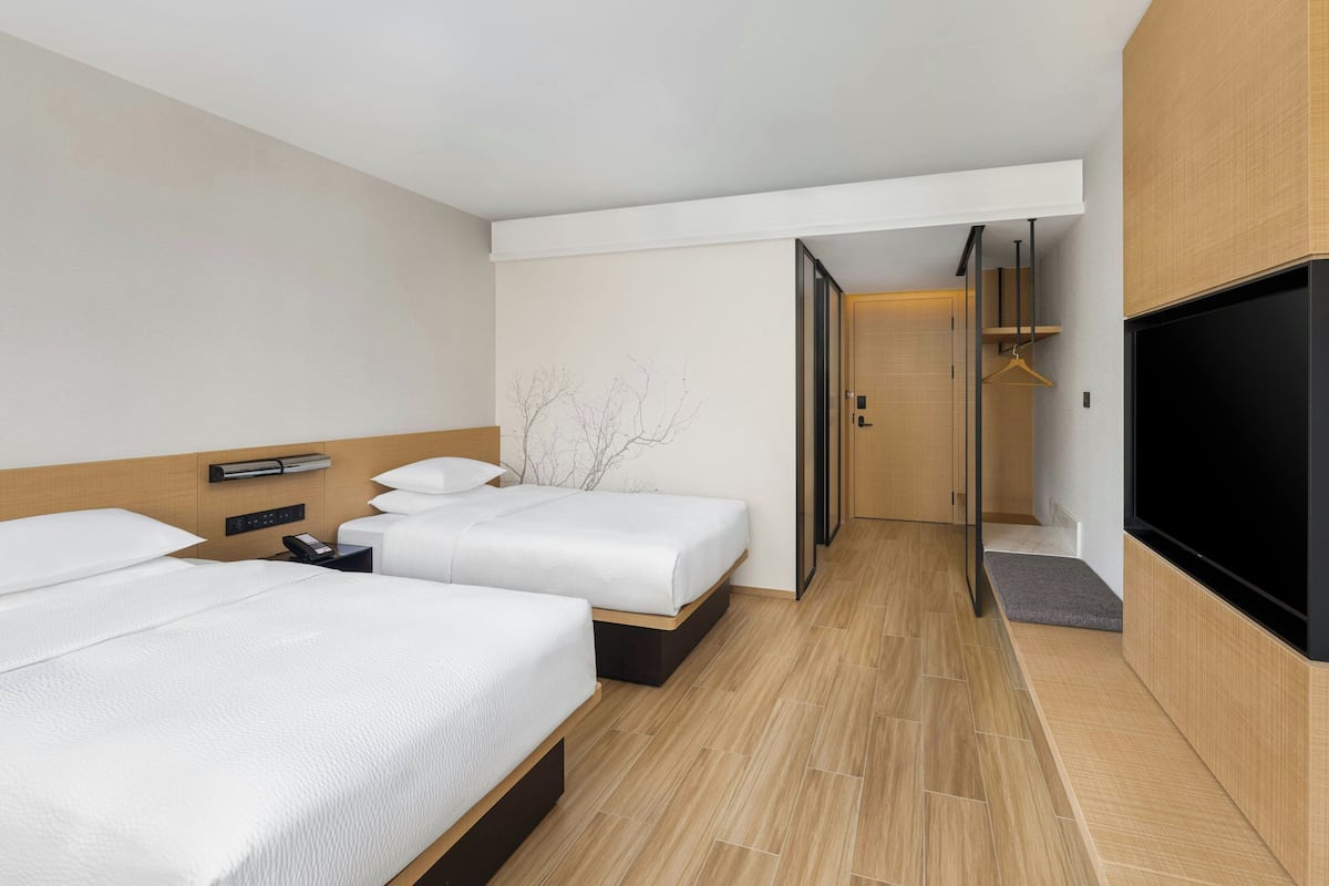 Une chambre d’hôtel avec deux lits, une télévision, une table de chevet et une armoire.