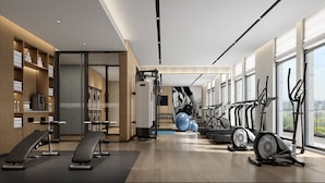 A modern gym with exercise equipment, a large window, and a view of the city. - Fairfield by Marriott Hangzhou Qiantang (Hangzhou)