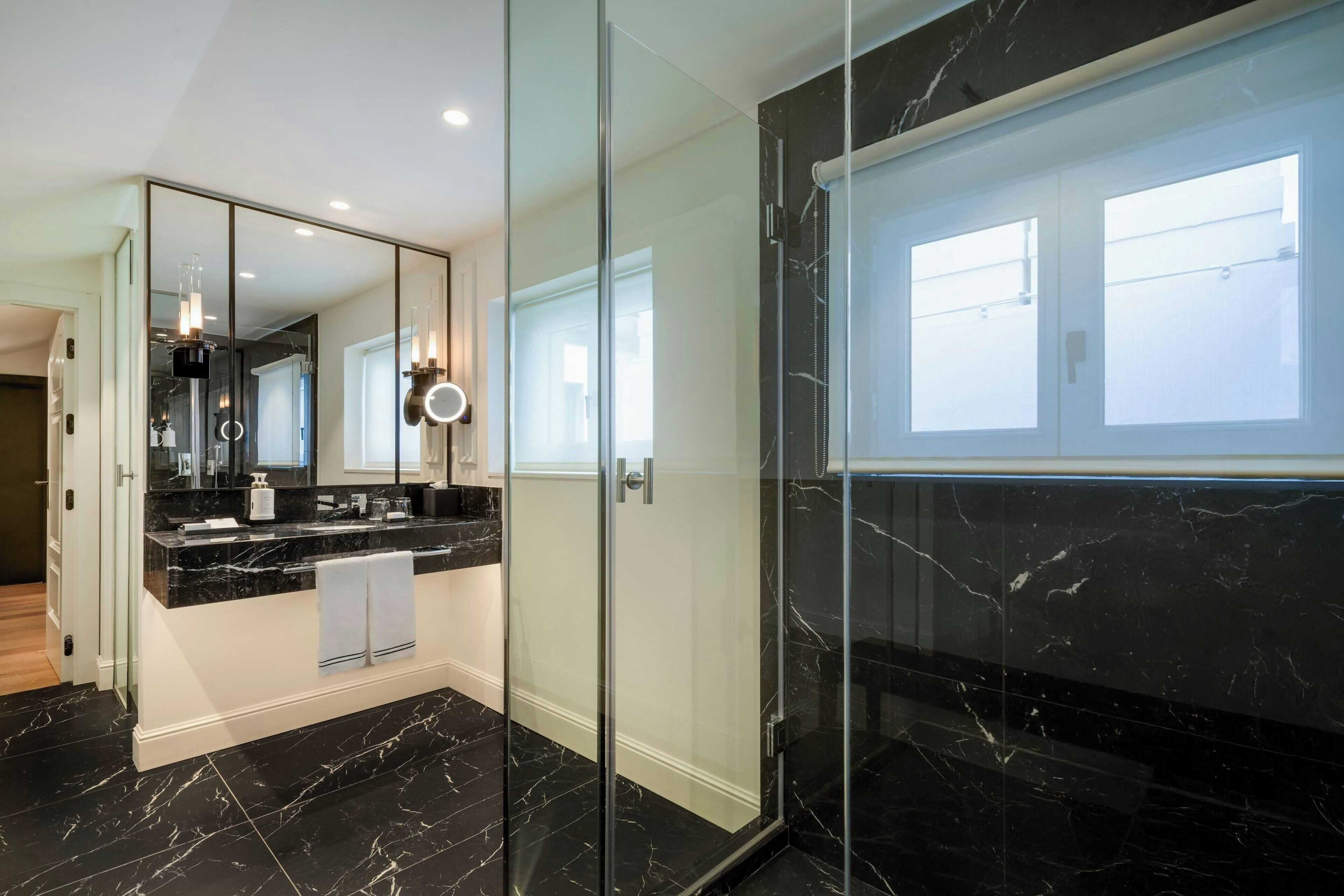 Une salle de bain moderne avec une douche à parois de verre, un grand miroir et un sol en marbre.