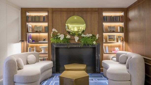Una sala de estar moderna con chimenea, dos sofás, una mesa de centro y una estantería con libros y objetos decorativos.