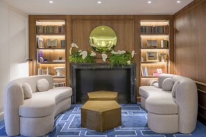 Un salon moderne avec une cheminée, deux canapés, une table basse et une bibliothèque contenant des livres et des objets décoratifs.