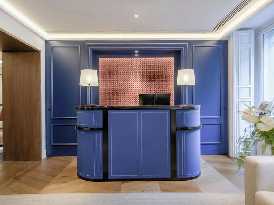 A reception area with a blue counter, two lamps, and a patterned wall.