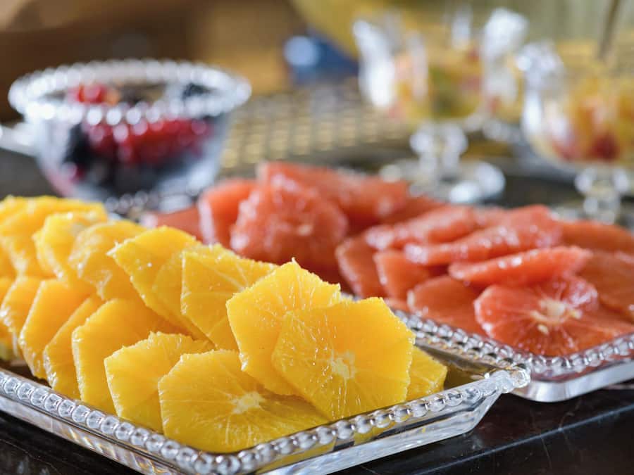 Un plateau de fruits comprenant des tranches d’oranges et de pamplemousses, présenté sur un plateau réfléchissant.