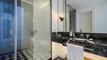A modern bathroom with a glass shower enclosure, a black marble countertop, and a large mirror.