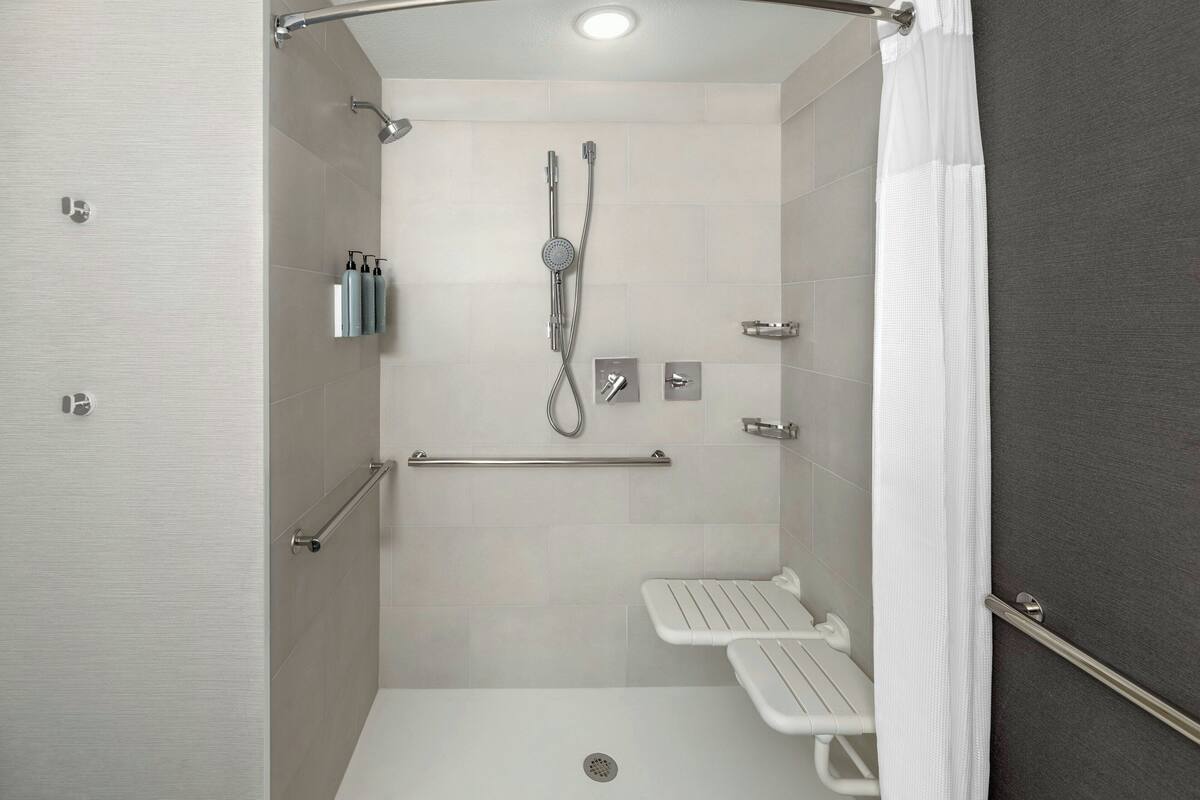 A modern shower area with a handheld showerhead, a wall-mounted faucet, and a handheld showerhead.