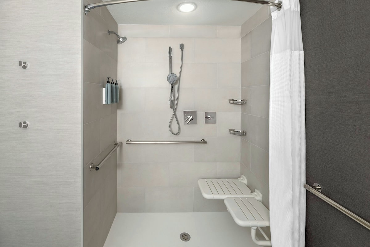 A modern shower area with a handheld showerhead, a wall-mounted faucet, and a handheld showerhead.