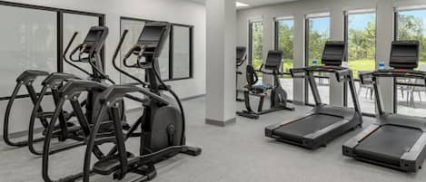A gym with treadmills, elliptical machines, and stationary bikes.