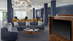 A modern lounge area with a sectional sofa, a glass coffee table, and a flat-screen TV.