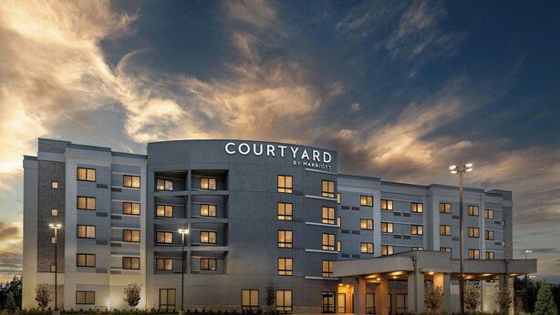 A Courtyard by Marriott hotel with a modern design, multiple floors, and a well-lit entrance.
