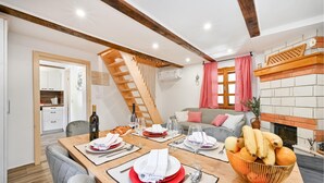 A dining area with a wooden table set for four, a sofa, and a fireplace.