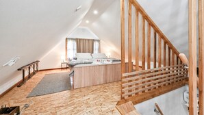 A bedroom with a wooden staircase, a bed with white bedding, a small bedside table, and a window with curtains.