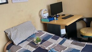 Un dormitorio con una cama, un escritorio con una computadora y una silla.