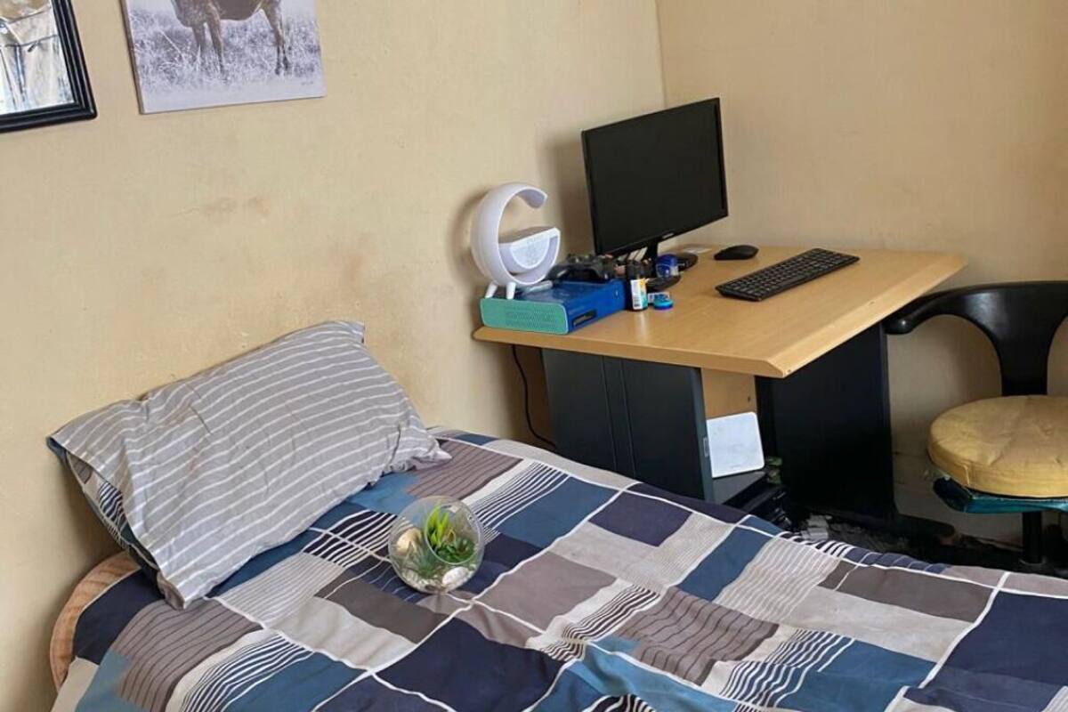 Une chambre à coucher avec un lit, un bureau avec un ordinateur et une chaise.