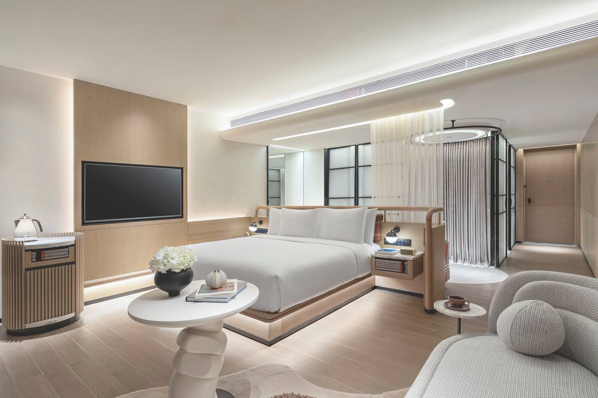 Una habitació d'hotel moderna amb un llit gran, un escriptori, una televisió i una zona de seients.
