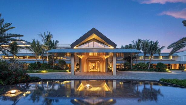 A modern hotel with a central atrium, a pool, and palm trees. - Hotel Indigo Hainan Clear Water Bay by IHG (Lingshui)