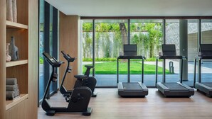 A modern gym with exercise equipment, large windows, and a view of a well-maintained garden. - Hotel Indigo Hainan Clear Water Bay by IHG (Lingshui)