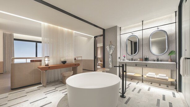 Un baño moderno con una bañera redonda grande, un tocador con dos espejos y una zona de estar con un banco.