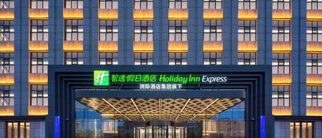 A modern building with a large entrance, illuminated signage, and a glass facade.