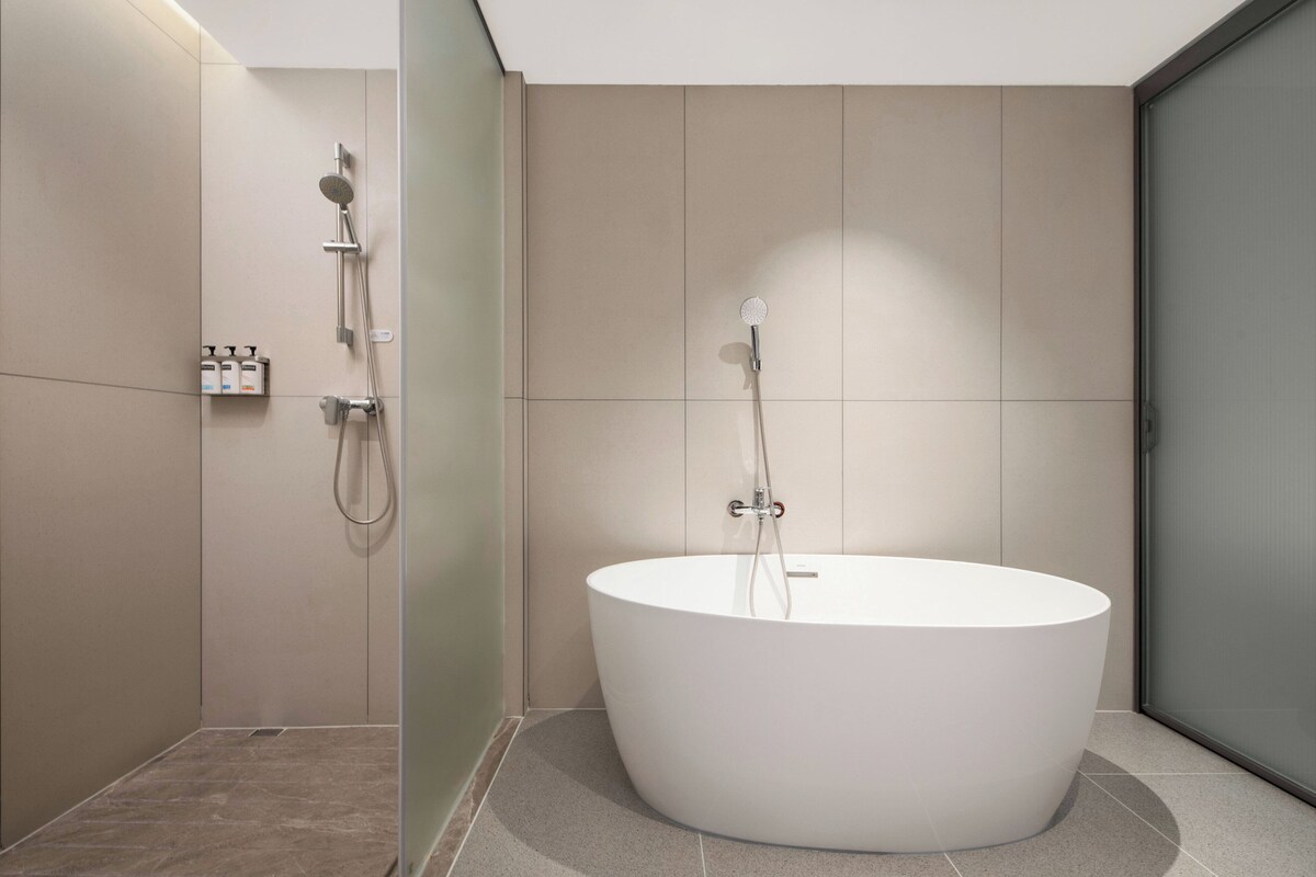 A modern bathroom with a freestanding bathtub, a shower area, and a glass-enclosed shower stall.