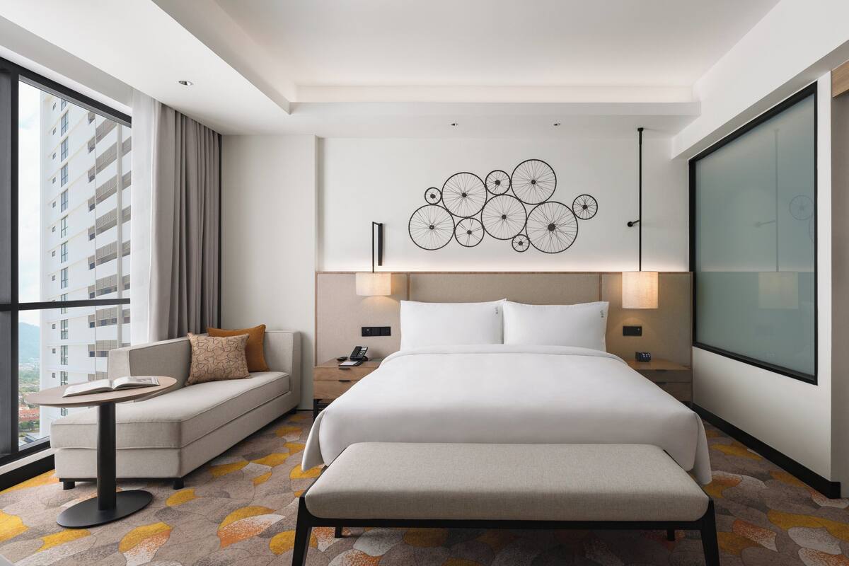 Une chambre d’hôtel moderne avec un grand lit, un canapé, une petite table et une armoire.