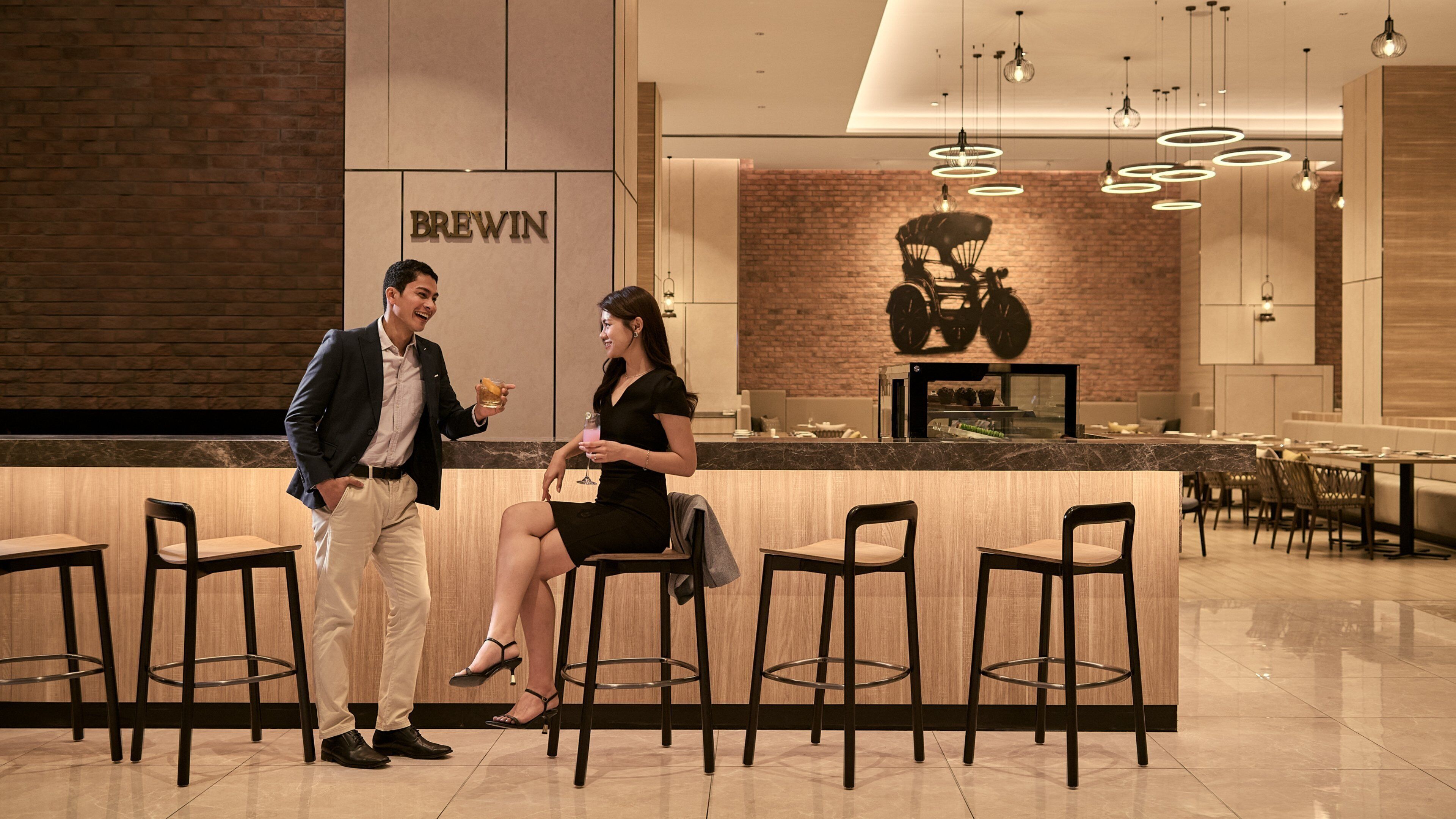 A modern interior with a BREWIN sign, a counter, and seating areas.