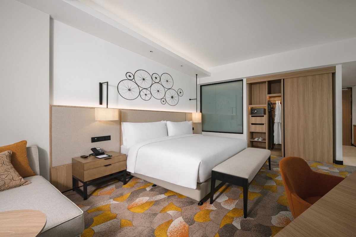 Een moderne hotelkamer met een groot bed, een bureau, een stoel en een kledingkast.