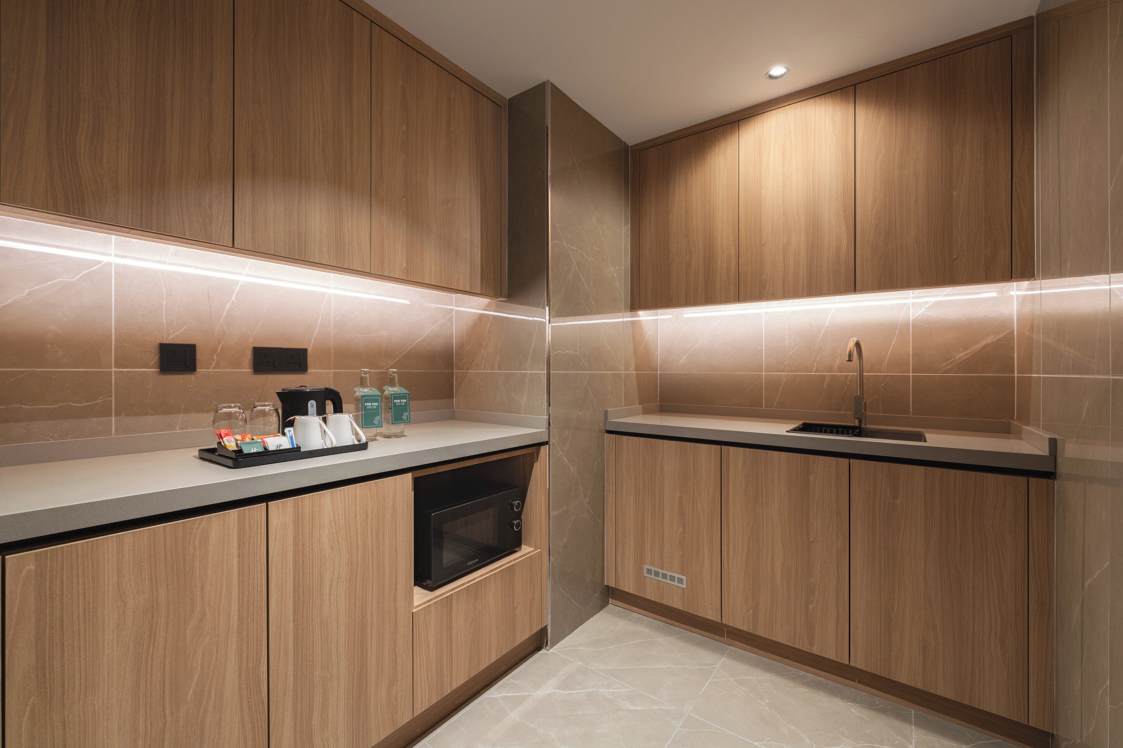 Une cuisine moderne avec des meubles en bois, un four à micro-ondes encastré et un évier en acier inoxydable.