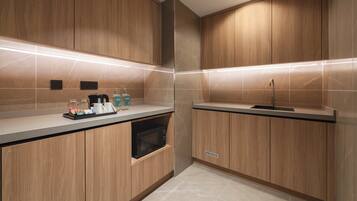 Une cuisine moderne avec des meubles en bois, un four à micro-ondes encastré et un évier en acier inoxydable.