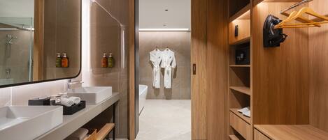Une salle de bain moderne avec un grand miroir, deux lavabos, une douche et des étagères en bois où sont rangées des serviettes et des articles de toilette.